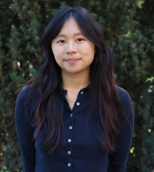 profile picture of Jade standing in front of a tall green tree and wearing a dark blue cardigan 